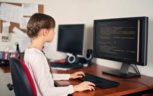 Little girl coding on desktop computer at home.